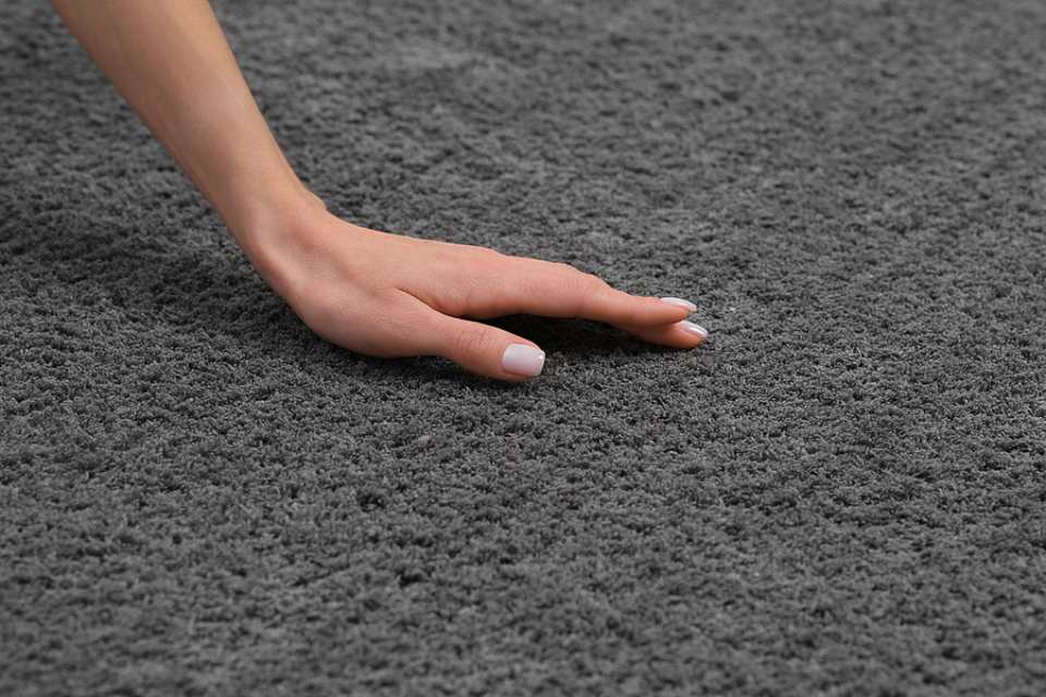 female hand touching new soft gray carpet